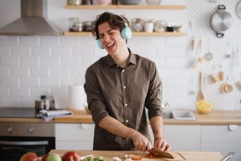 junger Mann singt während er kocht