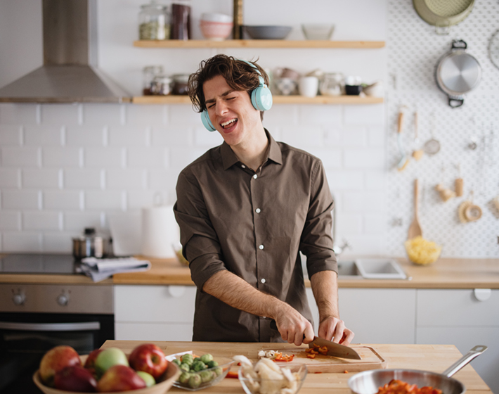 junger Mann singt während er kocht