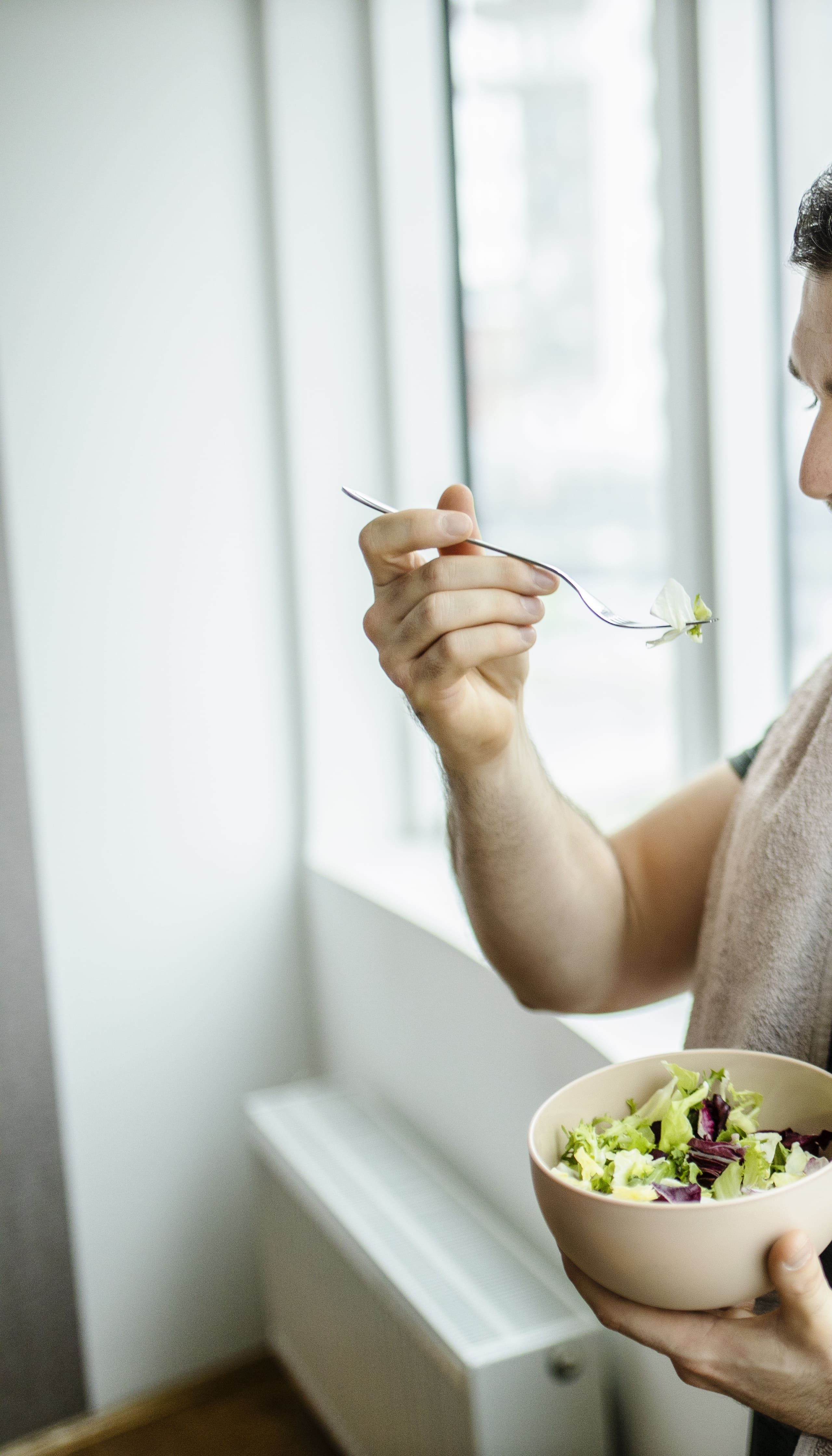Mann isst nach dem Sport einen Salat